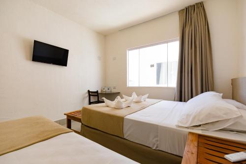 a hotel room with two beds and a television at Átrios Beach Hotel in Natal