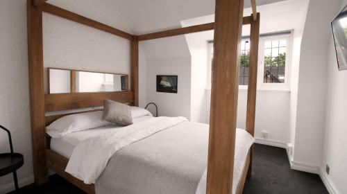 a bedroom with a wooden canopy bed with white sheets at One-Bedroom flat in Cheam Village in Cheam
