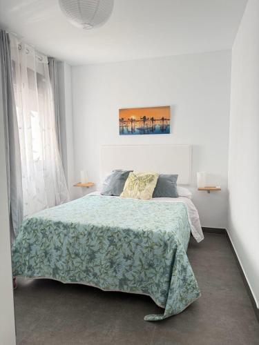 a white bedroom with a bed with a green blanket at FoFo Apartamento 78 in Cijuela