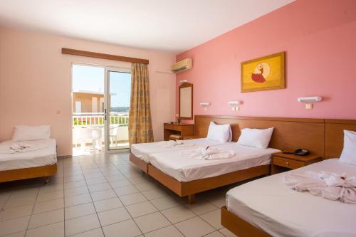 a hotel room with two beds and a balcony at Diagoras Hotel All Inclusive in Faliraki