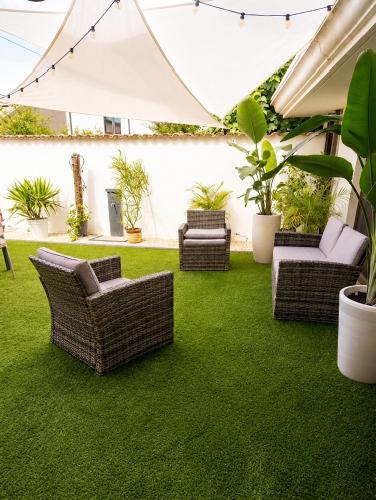 eine Terrasse mit Rasen, Korbstühlen und Pflanzen in der Unterkunft Pothos Apartment, Relax in Sardegna in Terralba