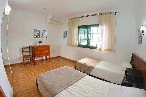 a bedroom with two beds and a desk and a window at Apartamentos La Palmera in Frontera