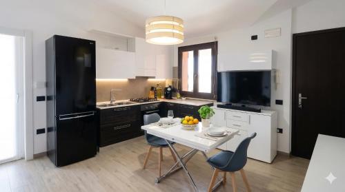 eine Küche mit Tisch und Stühlen sowie einem schwarzen Kühlschrank in der Unterkunft Pothos Apartment, Relax in Sardegna in Terralba