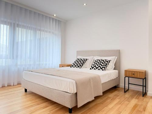 a white bedroom with a large bed and a window at Mouzinho Living Centro & Mar in Póvoa de Varzim