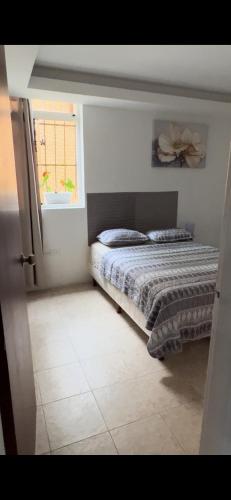 a bedroom with a bed and a window at APARTAMENTo CUMBRES ANDINAS 3 Hab 5 personas in San Cristóbal