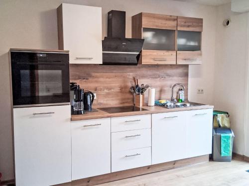 a kitchen with white cabinets and a black appliance at Holiday Home L by Interhome in Kövenig