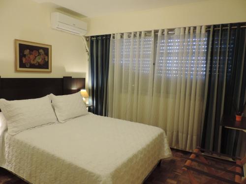 a bedroom with a bed and a window with curtains at Marazul in Montevideo