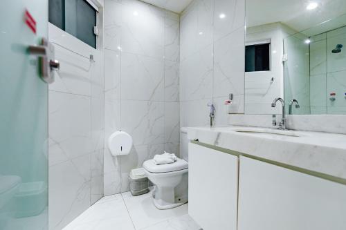 a white bathroom with a toilet and a sink at Átrios Beach Hotel in Natal