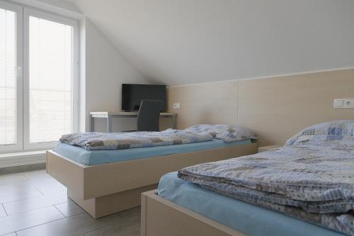 a bedroom with two beds and a desk and a tv at Apartmánový dům ROTOR in Kunowitz