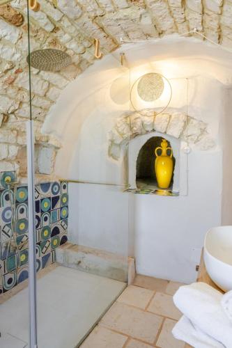 a bathroom with a glass shower with a yellow vase at Trulli boutique & suite in Santa Lucia