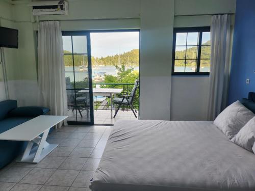 a bedroom with a bed and a balcony with a table at MSK Studios in Nydri