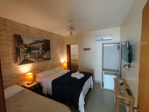a hotel room with two beds and a television at Pouso do parente in Pirenópolis