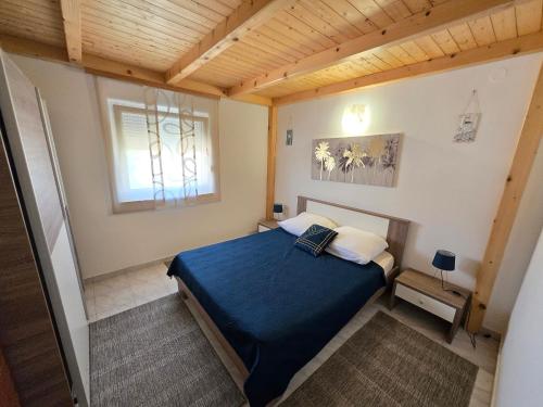 a bedroom with a blue bed and a window at Apartmani Kovač in Stara Novalja