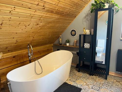 a bath tub in a bathroom with a wooden wall at Górska Chata w Górach Bystrzyckich in Niemojów