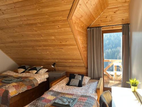 two beds in a room with a wooden ceiling at Górska Chata w Górach Bystrzyckich in Niemojów