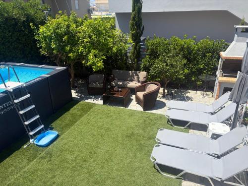 a backyard with lawn chairs and a swimming pool at GianAngelo Holiday Villa in Kremasti