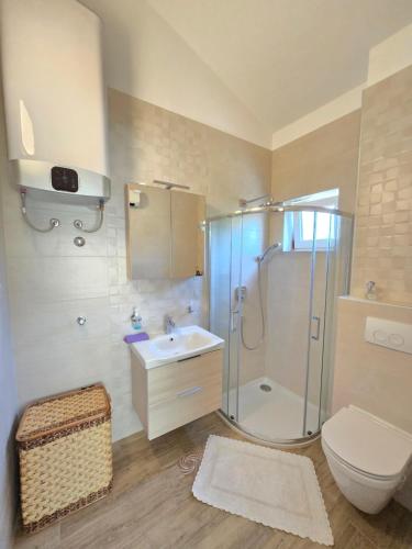 a bathroom with a shower and a toilet and a sink at Apartmani Kovač in Stara Novalja