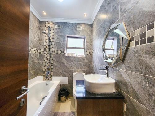 a bathroom with a sink and a tub and a mirror at Falcon Guest House in Harare