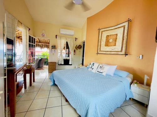 a bedroom with a blue bed and a bathroom at Bungalow Kuaa in Puerto Ángel