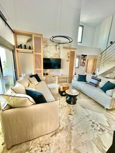 a living room with two couches and a staircase at Artion Jacuzzi Villa Nikiti in Nikiti