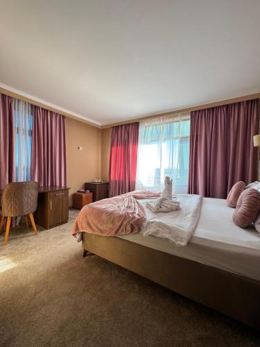 a bedroom with a bed with a teddy bear sitting on it at Hotel COLISEUM in Calafat