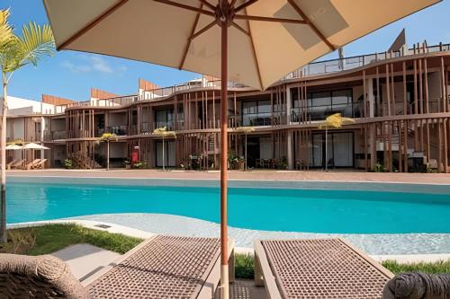 a resort with a swimming pool and an umbrella at Condo with Beach Access By MME in Tatuamunha