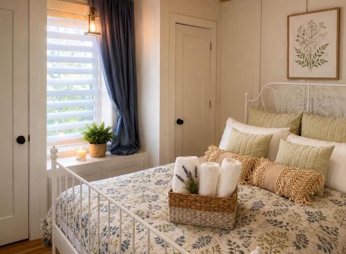 a white bed with a basket of towels on it at Honey & Hook Tiny Home with Breakfast in St. Catharines