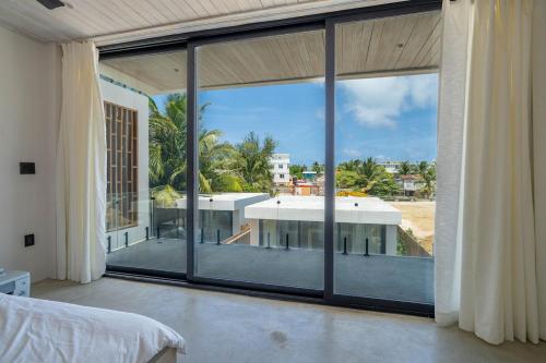 a bedroom with a large window with a view of a building at LuxVilla Modern Beachfront in the Village in Caye Caulker
