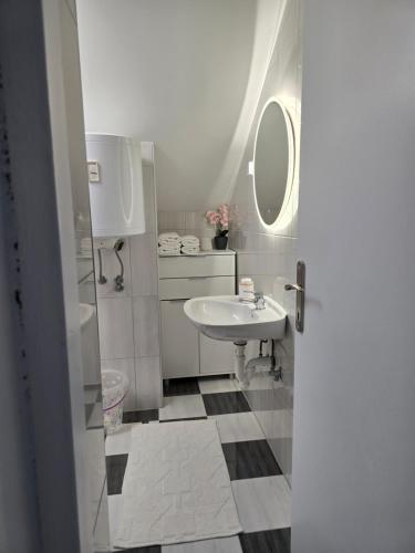 a white bathroom with a sink and a mirror at Apartmani Zinda in Sukošan
