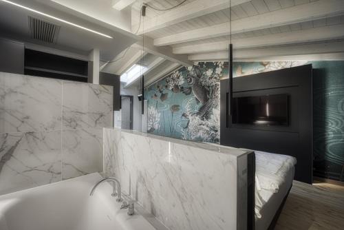 a bathroom with a tub and a tv on the wall at M Loft - adults only in Malcesine