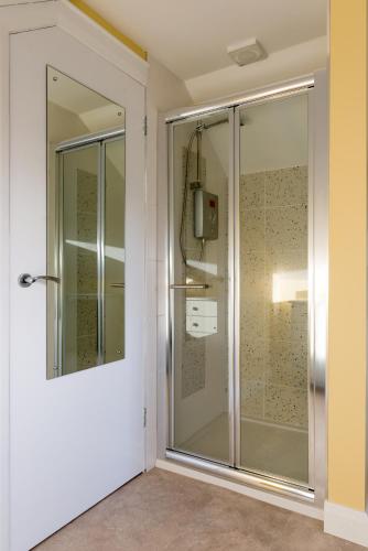 a glass shower in a room with a wall at Ashbrook House Apartments in Dungannon