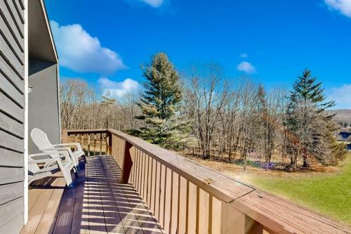 a deck with a chair and a view of the woods at Nimba Cabin in Oakland