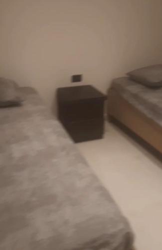 a bedroom with two beds and a nightstand next to a bed at جسر السويس نفرتاري in Obour