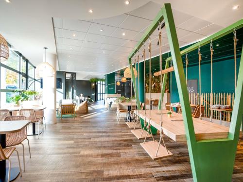 a restaurant with tables and chairs and a green wall at ibis Styles Chatenay Malabry Paris Sud in Châtenay-Malabry