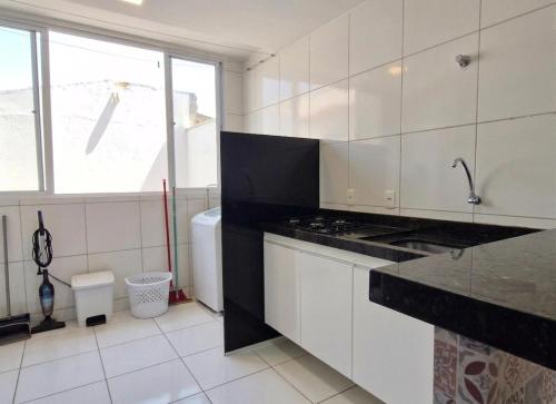 a kitchen with white cabinets and a black counter top at Apartamento Moto Chico Petrolina in Petrolina