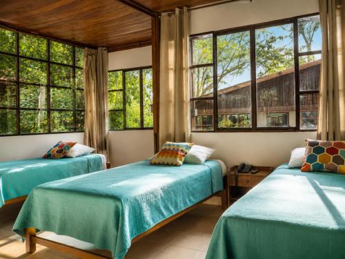 two beds in a room with windows at CasaBosque in Tarapoto