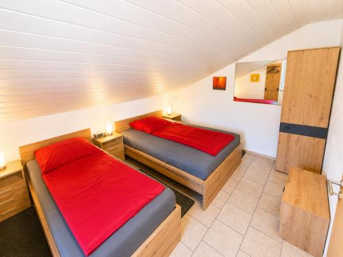 two beds in a small room with red sheets at Stadldorf» Ferienwohnung Wagner in Kirchroth