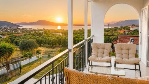 a balcony with two chairs and a view of the ocean at Villa Aelia Luxury Maisonette in Salamina