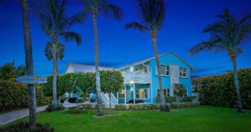 a blue house with palm trees in front of it at Dual En-Suite Corner Unit - Sunrise Views in Fort Pierce