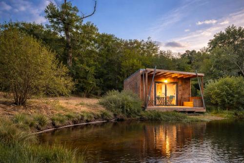 a small wooden cabin next to a body of water at Domaine Ecoline in Sadirac