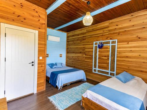 two beds in a room with wooden walls at Izgen Bungalows in Cıralı