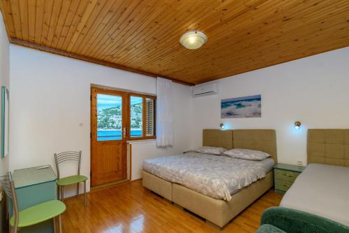 a bedroom with a bed and a wooden ceiling at Apartments Steps from the Sea in Donja Klada