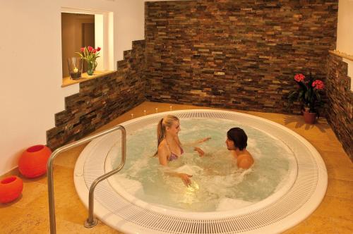 duas mulheres numa banheira de hidromassagem num quarto em Hotel Markushof 3***S em Valdaora