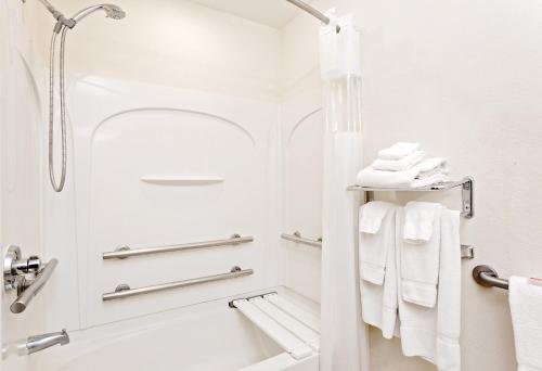 y baño con ducha, bañera y toallas. en Microtel Inn & Suites by Wyndham Middletown, en Middletown