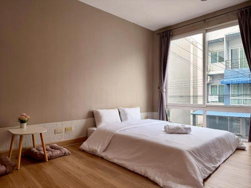 a bedroom with a large white bed and a window at The Modern Nest in Ban Bang Chan