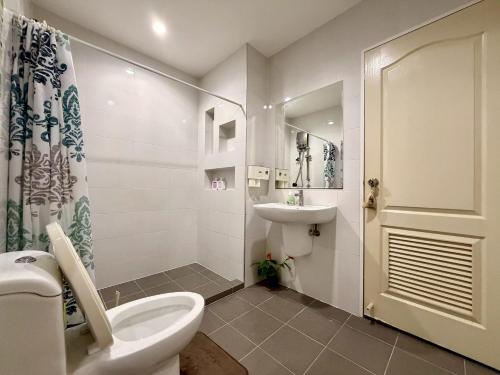 a white bathroom with a toilet and a sink at The Modern Nest in Ban Bang Chan