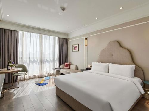 a bedroom with a large bed and a living room at Mercure Beijing City Center in Beijing