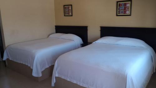 two beds in a room with white sheets at Hotel palma de oro in Puerto Peñasco