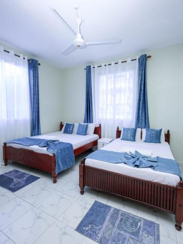 two beds in a bedroom with blue curtains at Serene Coastal Suites in Mombasa