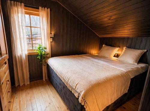 a bedroom with a large bed with a window at Forest Cabin by the Water in Ålesund